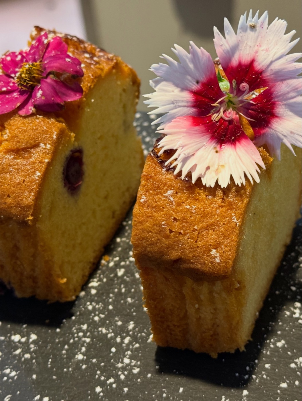 Two slices of cake dusted with sugar and finished with edible flowers